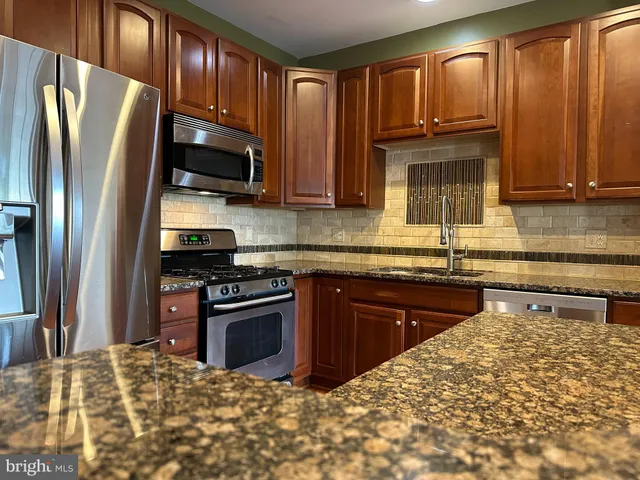a kitchen with stainless steel appliances granite countertop a refrigerator stove top oven and sink