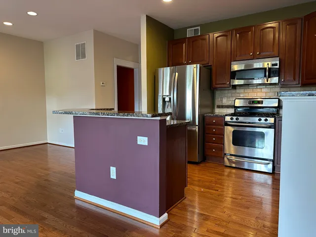 a kitchen with stainless steel appliances granite countertop a refrigerator stove and microwave