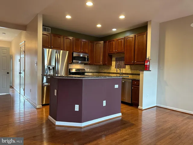a kitchen with kitchen island granite countertop wooden cabinets and stainless steel appliances