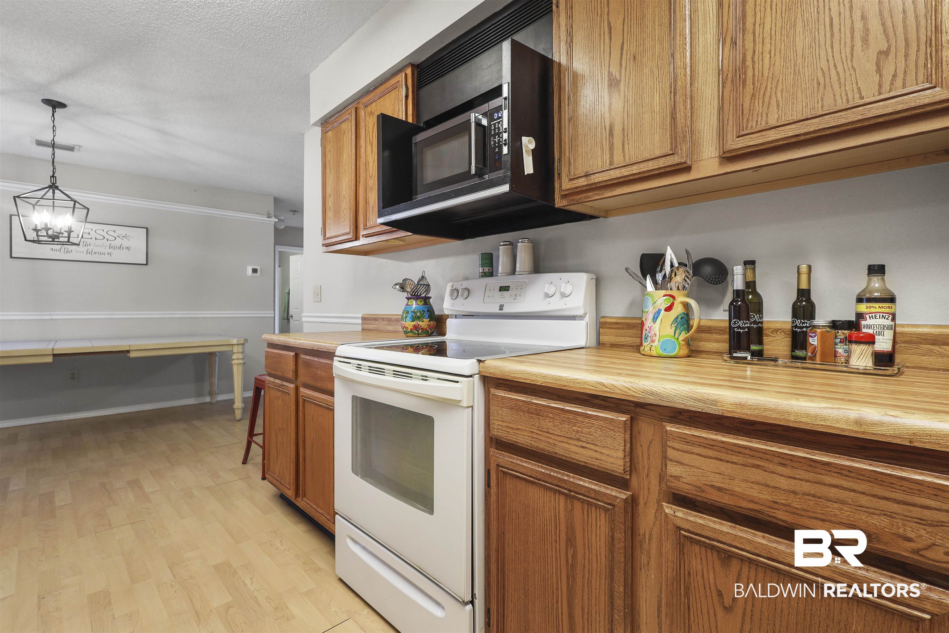 507 West Amanda Avenue Foley, AL 36535 - Photo 14 of 23 Kitchen with light hardwood / wood-style floors, pendant lighting, a textured ceiling, white electric range, and a notable chandelier