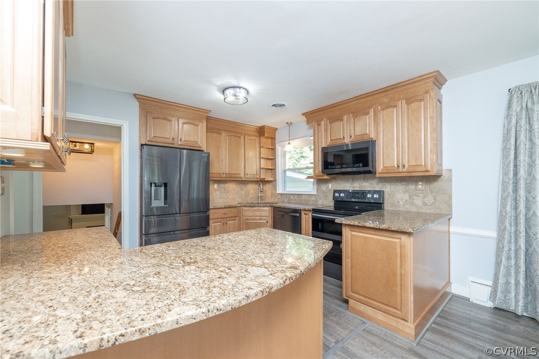 a kitchen with stainless steel appliances kitchen island granite countertop a refrigerator and a stove top oven