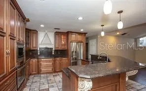 a kitchen with stainless steel appliances granite countertop a sink a stove and a refrigerator