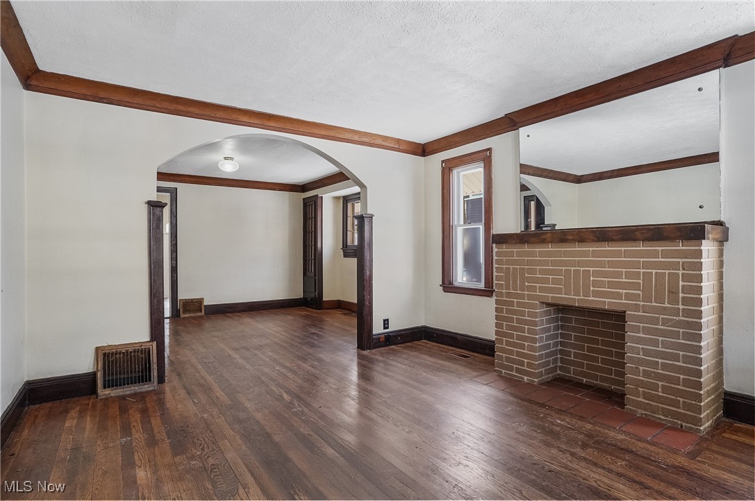 1618 Hampton Road Akron, OH 44305 - Photo 4 of 30 Unfurnished living room with a textured ceiling, a brick fireplace, dark wood-type flooring, and crown molding