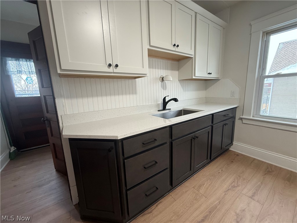 3612 Riverside Avenue Cleveland, OH 44109 - Photo 4 of 22 Two-tone cabinetry featuring white upper cabinets and dark lower cabinets, complemented by a light-toned countertop and an undermount sink with a matte black faucet