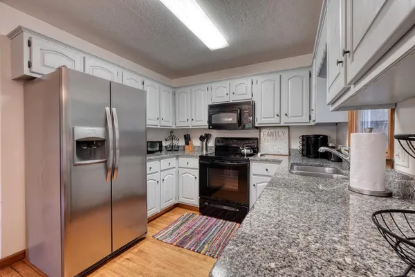 a kitchen with granite countertop a sink stove top oven and cabinets