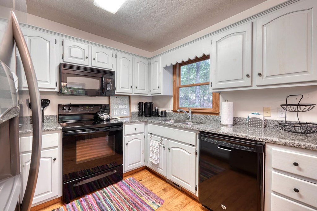 3739 Pat Colwell Road Blairsville, GA 30512 - Photo 17 of 55 a kitchen with granite countertop white cabinets sink and stainless steel appliances