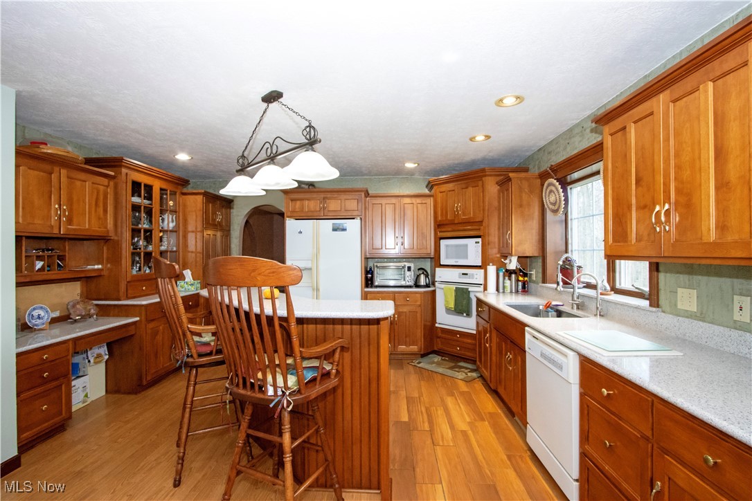 11079 Colwill Road Gambier, OH 43022 - Photo 13 of 41 Kitchen with brown cabinets, a center island, light wood-type flooring, and white appliances