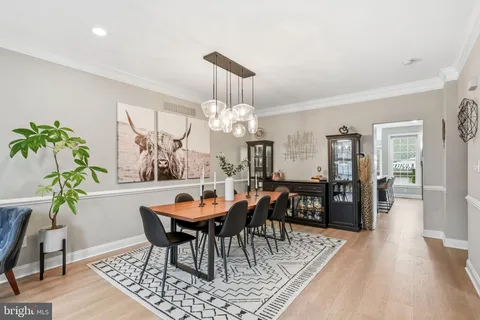 a dining room filled chandelier and wooden floor