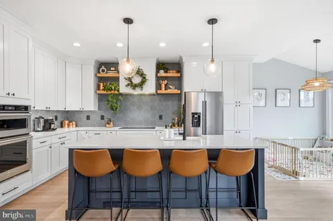 a kitchen with stainless steel appliances granite countertop a sink a stove a dining table and chairs