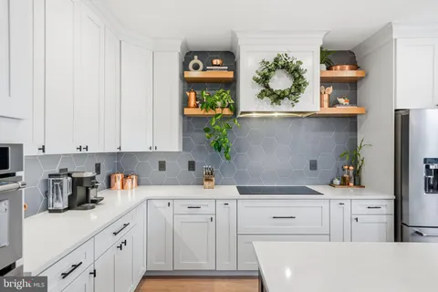 a kitchen with white cabinets and wooden floor