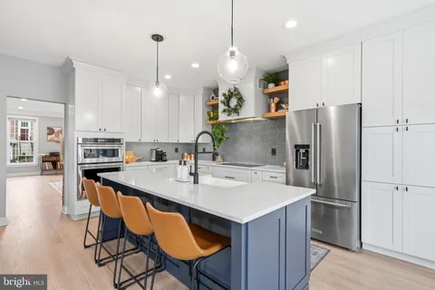 a kitchen with kitchen island a refrigerator a stove a sink and chairs