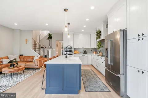 a large kitchen with stainless steel appliances kitchen island granite countertop a refrigerator a stove a sink and a dining table with wooden floor