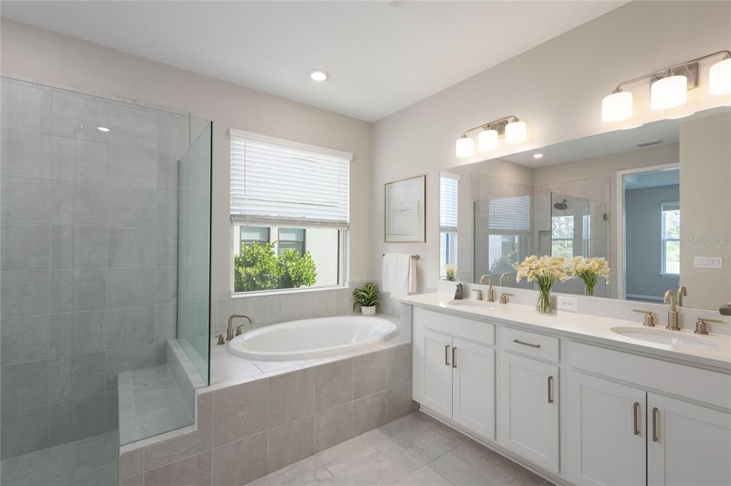 5604 Blue Reef Place Nokomis, FL 34275 - Photo 16 of 45 a spacious bathroom with a double vanity sink a large mirror and a bathtub