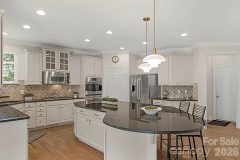 a kitchen with stainless steel appliances granite countertop white cabinets and window