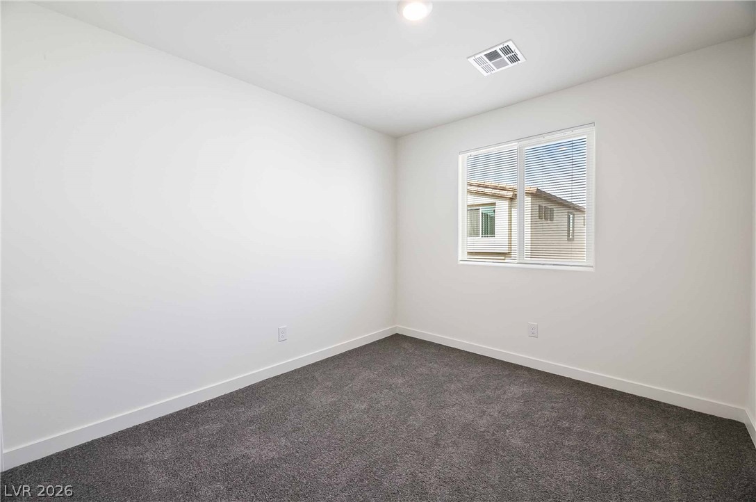 12749 Epperly Street Henderson, NV 89044 - Photo 14 of 22 A well-lit bedroom features plush gray carpeting and a wide window offering exterior views.