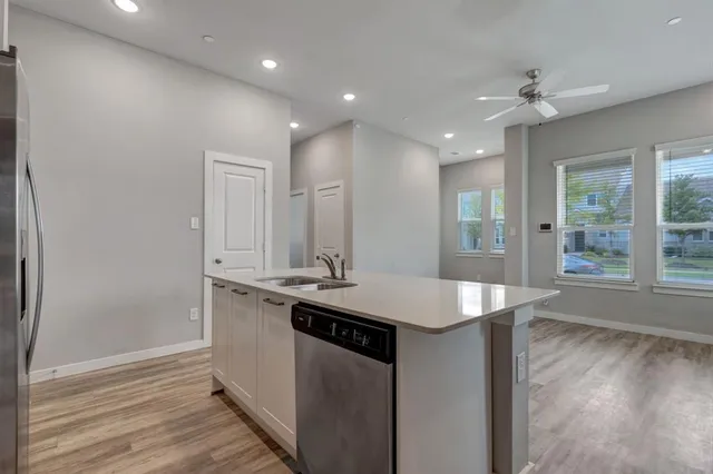 a kitchen with stainless steel appliances granite countertop a sink and a wooden floor