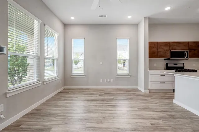 a view of empty room with wooden floor and a window