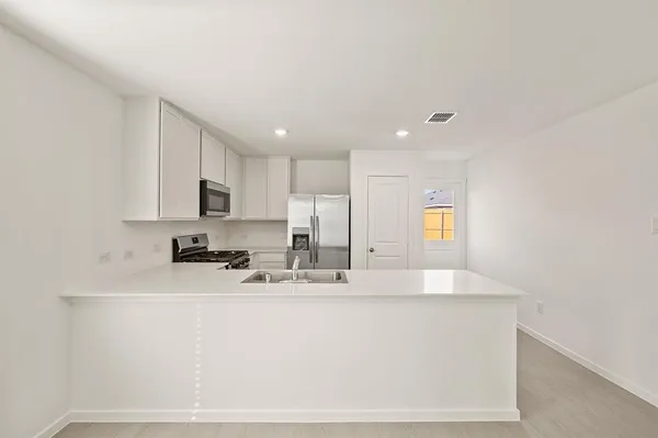 a large white kitchen with kitchen island a sink stainless steel appliances and cabinets
