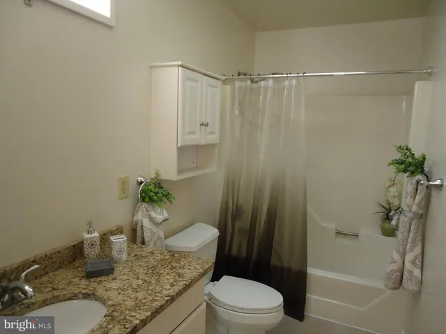 a bathroom with a granite countertop sink a toilet and shower