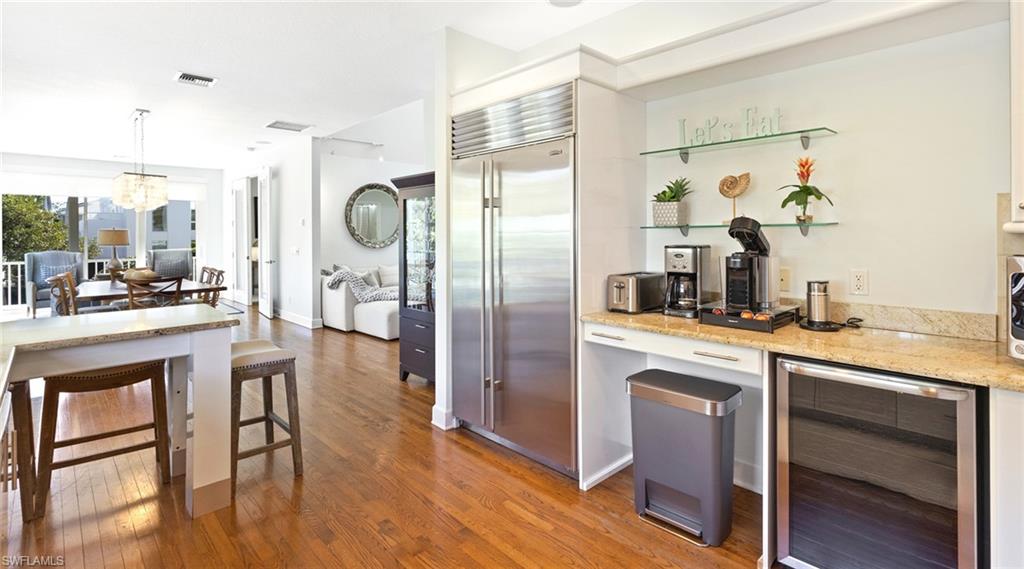 877 7th Street South Naples, FL 34102 - Photo 12 of 45 Kitchen featuring wine cooler, stainless steel built in fridge, light stone countertops, light wood-style floors, and suspended lighting