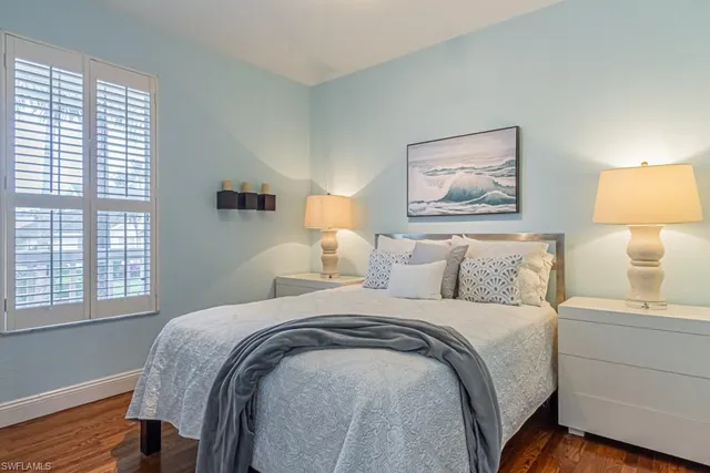 a bedroom with bed a lamp and a window