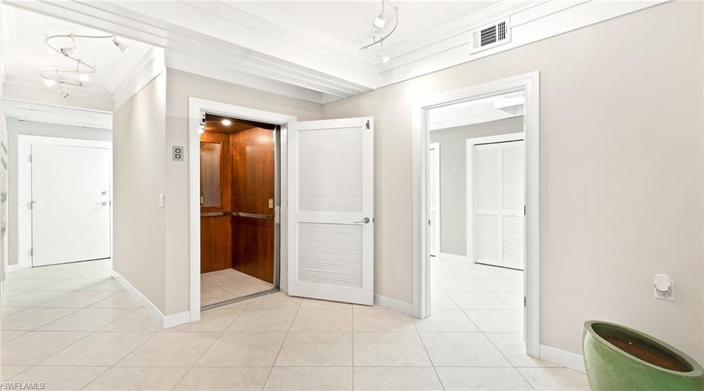 877 7th Street South Naples, FL 34102 - Photo 26 of 45 Hallway featuring elevator, ornamental molding, light tile patterned floors, and track lighting