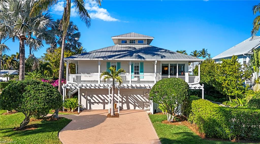 877 7th Street South Naples, FL 34102 - Photo 42 of 45 Raised beach house featuring decorative driveway, a standing seam roof, a garage, and a balcony