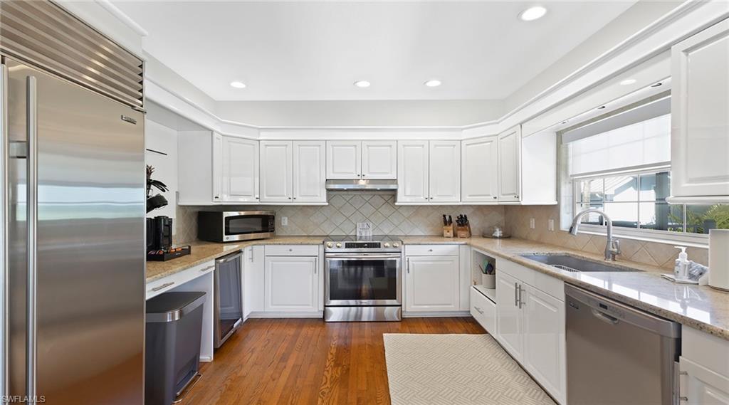 877 7th Street South Naples, FL 34102 - Photo 9 of 45 Kitchen featuring stainless steel appliances, white cabinetry, light stone countertops, and recessed lighting