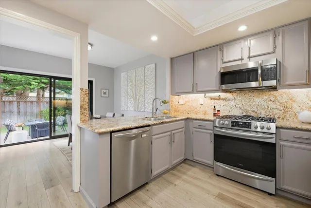 a kitchen with stainless steel appliances granite countertop a stove top oven a sink and a microwave