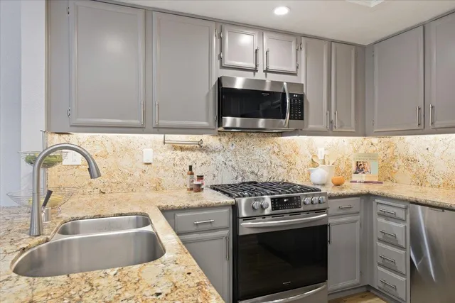 a kitchen with granite countertop a sink stove and microwave