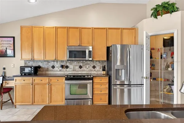 a kitchen with stainless steel appliances kitchen island granite countertop a table chairs and a wooden floor