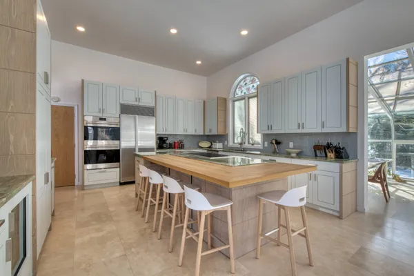 a large kitchen with kitchen island a large counter top space a sink stainless steel appliances and cabinets