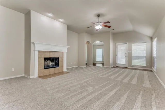 a view of an empty room with chandelier fan and fire place