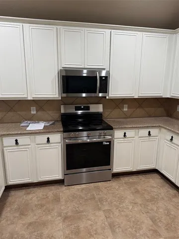 a kitchen with granite countertop white cabinets and stainless steel appliances