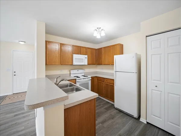 a kitchen with a refrigerator a stove a sink cabinets and wooden floor