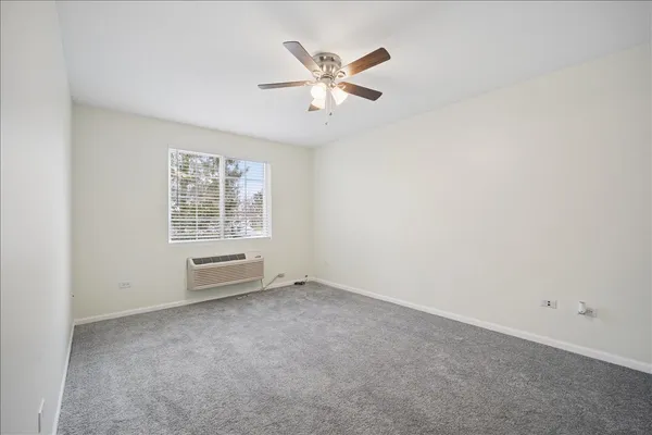 an empty room with ceiling fan and windows