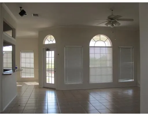 an empty room with wooden floor fan and windows