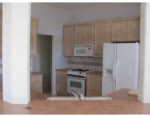 a kitchen with granite countertop a refrigerator stove and cabinets