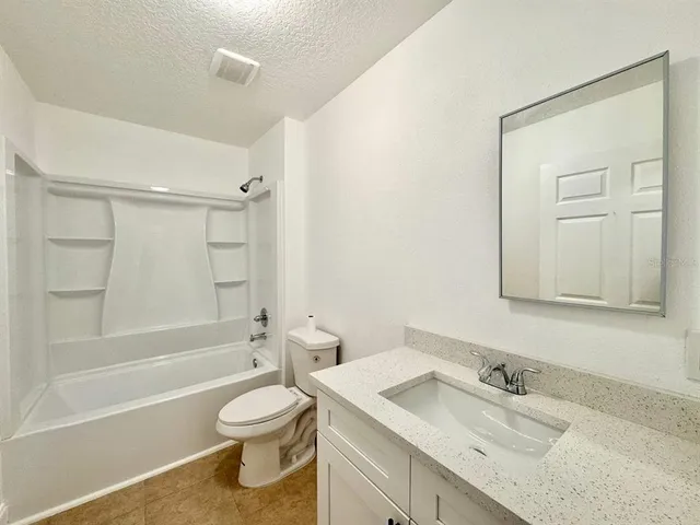 a bathroom with a granite countertop sink toilet a mirror and shower