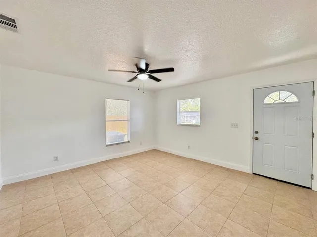 an empty room with windows and fan