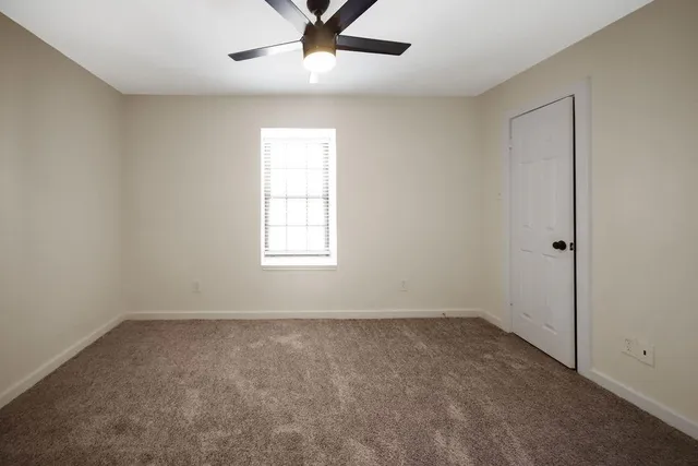an empty room with a window and ceiling fan