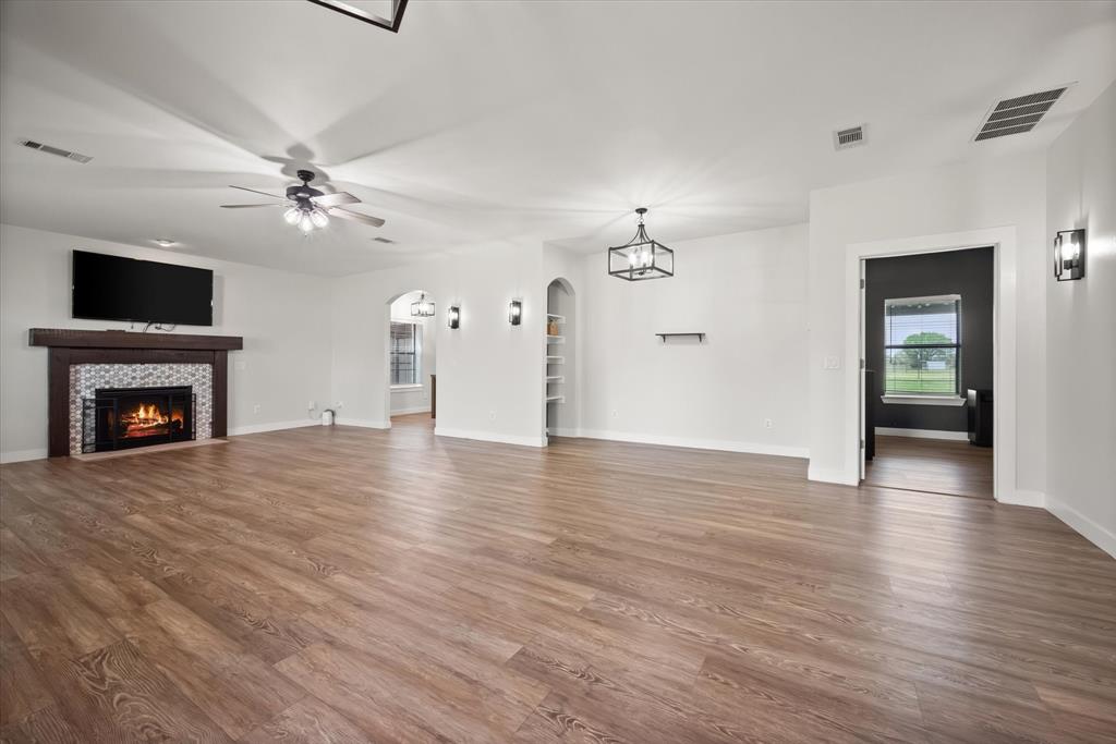 504 Texas Street Tioga, TX 76271 - Photo 18 of 38 a view of an empty room with wooden floor fireplace and a window