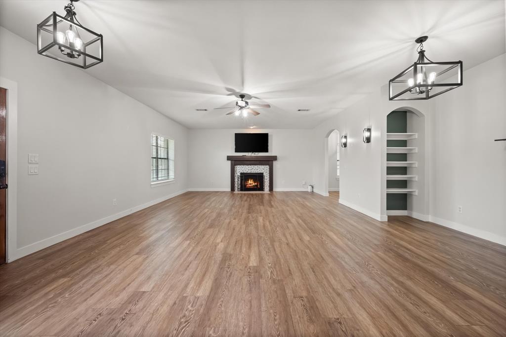 504 Texas Street Tioga, TX 76271 - Photo 22 of 38 a view of a livingroom with a kitchen wooden floor and a ceiling fan