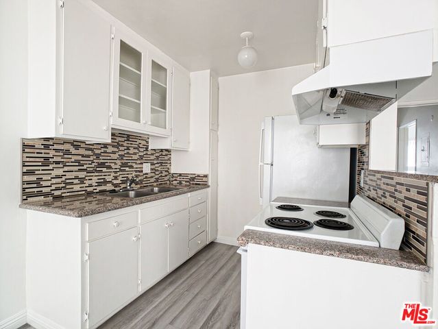a kitchen with granite countertop a sink stove and refrigerator
