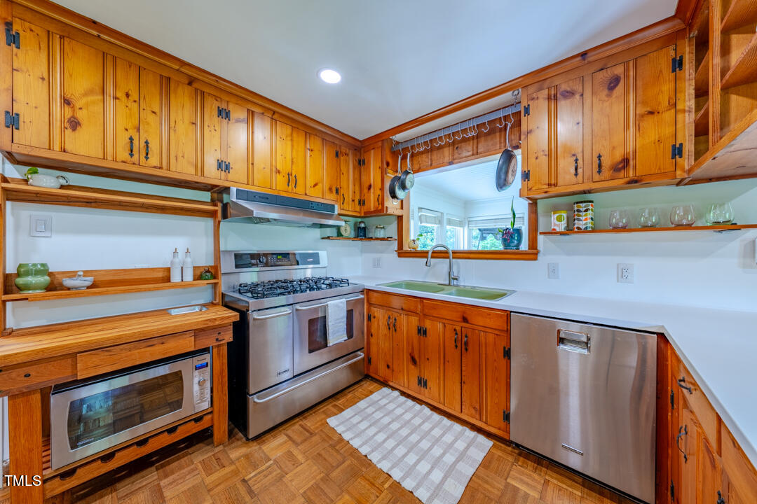 4621 Erwin Road Durham, NC 27705 - Photo 8 of 40 a kitchen with stainless steel appliances granite countertop wooden cabinets and a stove top oven