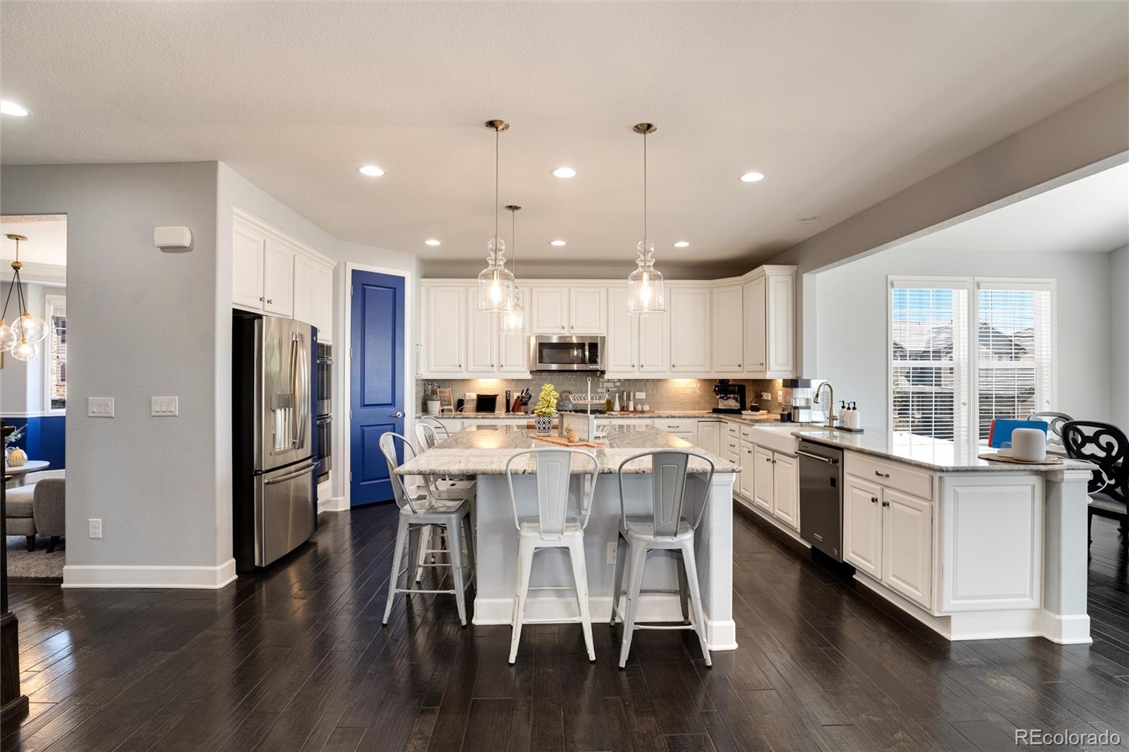 14390 Double Dutch Loop Parker, CO 80134 - Photo 12 of 50 a kitchen with stainless steel appliances kitchen island granite countertop a refrigerator a stove a sink a dining table and chairs with wooden floor