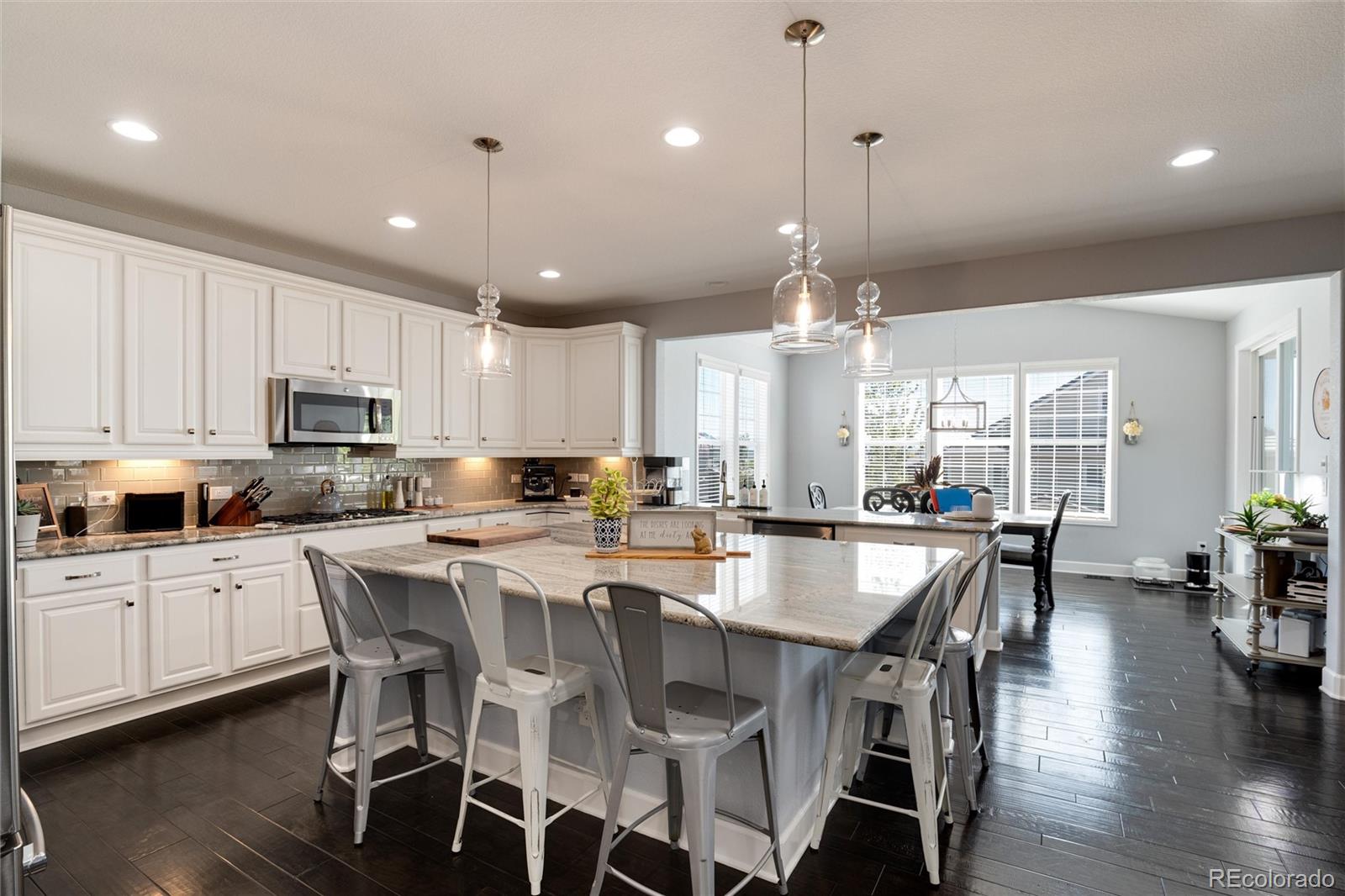 14390 Double Dutch Loop Parker, CO 80134 - Photo 14 of 50 a large kitchen with kitchen island a dining table chairs and white cabinets