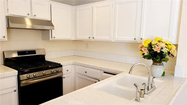 a kitchen with stainless steel appliances granite countertop a sink a stove and white cabinets