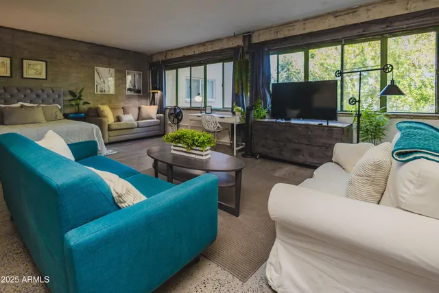 a living room with furniture a flat screen tv and a large window