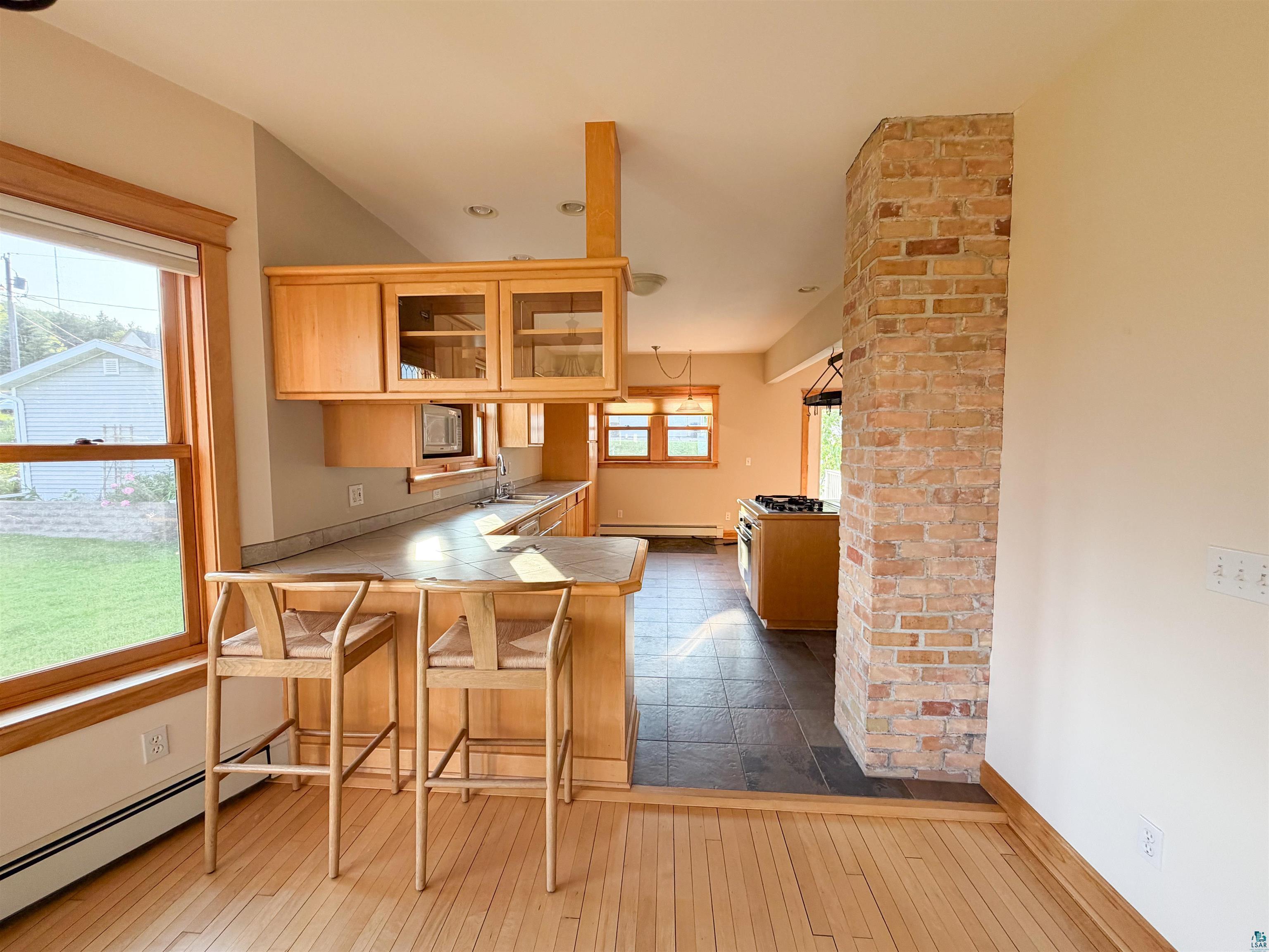 13 West 8th Street Duluth, MN 55806 - Photo 8 of 57 Kitchen with light wood cabinetry, a tiled countertop, and a built-in breakfast bar
